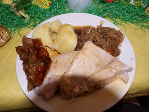 Ein Teller mit Knödeln, Sauerkraut, Schweinebraten und Sauce - der Tisch ist österlich dekoriert