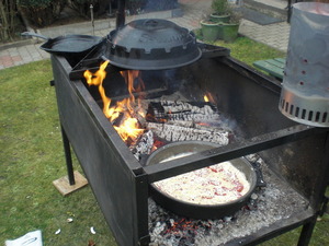 Ein Gusstopf mit Pizza neben dem Lagerfeuer