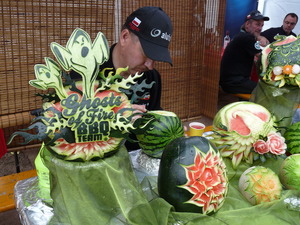 Ein Mann schnitzt Wassermelonen. Auf der Melone im Vordergrund steht: Ghosts of Fire BBQ Team