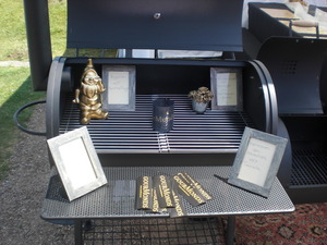 Ein neuer Smoker - auf dem Rost stehen Bilderrahmen mit den Namen der Gänge und GourMonds Aufkleber