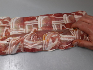 Schweinefilet wird in Geflecht aus Baconscheiben eingerollt