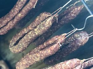 Salami hängt an Haken im Räucherschrank