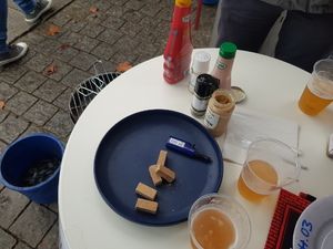 Stehtisch mit Bier, Saucenflaschen und Teller