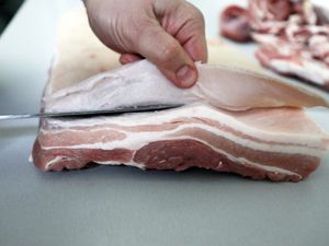 Die Schwarte wird vom Schweinebauch abgeschnitten