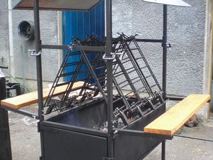 Lachsgrill Naantali mit leeren Haltern über der Feuerstelle