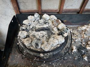 Dutch Oven in der Glut mit Asche auf dem Deckel