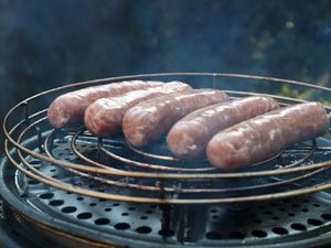 Rohe Würste auf dem Rost im Tischgrill