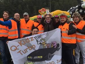 Team in orangen Warnwesten mit Q-Kidz-Turbo-Fahne