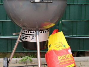 Kugelgrill mit Kohlekorb, daneben ein Sack Buchenholzkohle