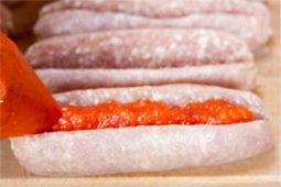 Ajvar wird in die aufgeschnittene Bratwurst gespritzt