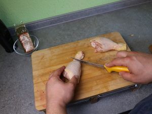 Hähnchenunterschenkel werden auf dem Brett eingeschnitten