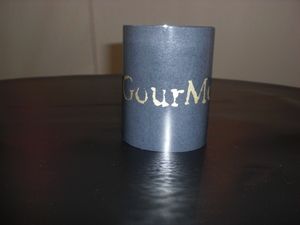 Ein runder, schwarzer Teelichthalter mit dem Aufdruck 'Gourmonds'