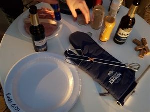 Grillzange, Handschuh, Teller und Saucenflaschen auf dem Tisch
