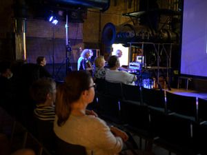 Zuschauer in einer Halle vor einer Bühne mit Musikern
