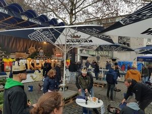 Besucher und Grillstationen unter Kronen-Schirmen auf dem Platz
