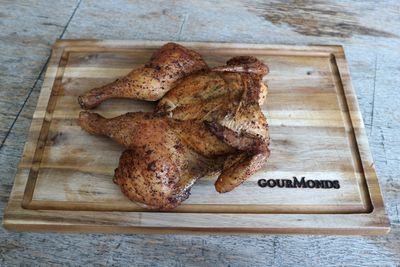 Gegrilltes, flach aufgeschnittenes Hähnchen auf einem GourMonds-Brett