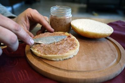 Kochmettwurst wird auf ein Brötchen gestrichen