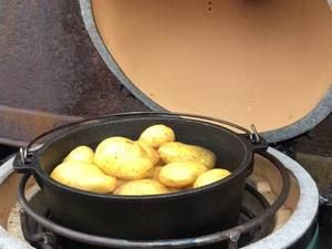 Dutch Oven mit Kartoffeln im geöffneten Keramikgrill