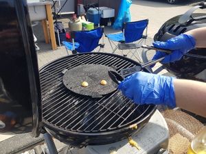 Kartoffeltaler werden mit Handschuhen auf der Grillplatte gewendet