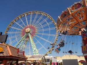 Riesenrad und Kettenkarussell vor blauem Himmel