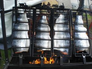 Vier Lachshälften hängen über den Flammen