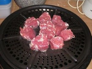 Fleischstücke auf der Grillplatte des Cobb