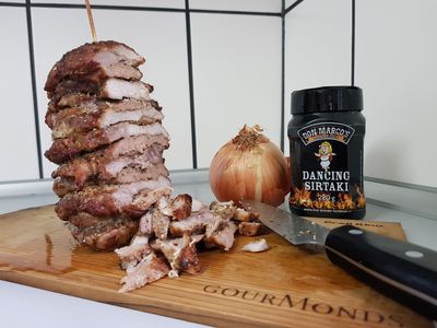 Gyros-Spieß neben Zwiebel und Gewürzdose, davor geschnittenes Gyros