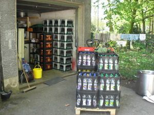 Eine Palette mit Wasserkisten. Im hintergrund eine Garage mit vielen Bierkisten.