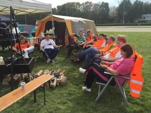 Team in Warnwesten sitzt auf Campingstühlen vor dem Zelt