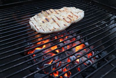 Naanbrot mit Grillstreifen auf Grillrost. Darunter glühende Kohlen