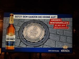 Werbebildschirm „Setzt dem Ganzen die Krone auf“ bei Nacht
