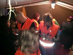 Team in Warnwesten im beleuchteten Zelt am Abend
