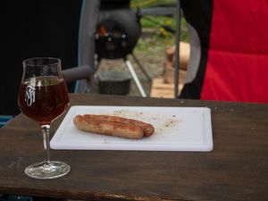 Glas Bier und eine Bratwurst auf einem Brett
