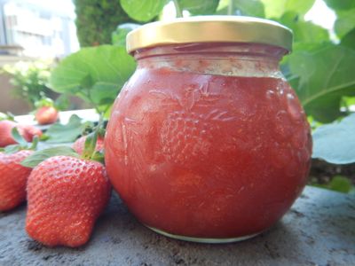 Glas Erdbeermarmelade vor frischen Erdbeeren