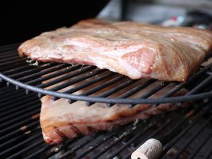 Schweinebauch liegt zum Räuchern auf dem Grillrost