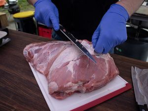 Schweinenacken wird auf einem Schneidebrett pariert